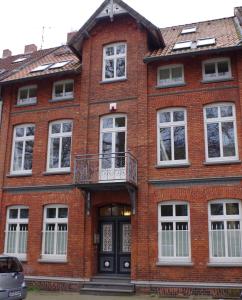 ein rotes Backsteingebäude mit einem Balkon und einer Tür in der Unterkunft Villa Friedenstraße 11 in Lüneburg