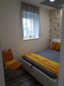 ein Schlafzimmer mit einem Bett, einem Fenster und einem Stuhl in der Unterkunft Belvárosi apartman in Szigetvár
