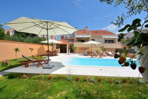 a swimming pool with an umbrella and a house at Villa Zupan in Zadar +41 photos