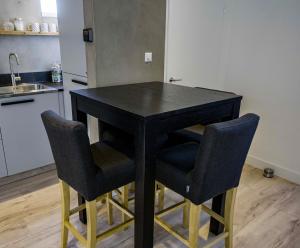 アルクマールにあるBackyardの黒いテーブルと椅子2脚付きのキッチン付