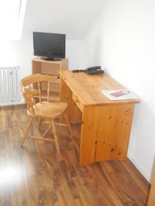 a wooden desk with a chair and a television at Hotel Garni am Hechenberg in Mainz