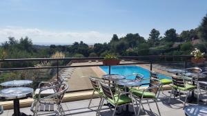 einen Balkon mit Tischen und Stühlen sowie einen Pool in der Unterkunft Le Petit Vue Mer in La Croix-Valmer