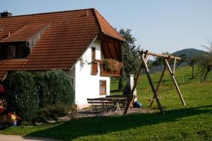uma pequena casa branca com uma mesa e um baloiço em Ferienwohnung em Seelbach