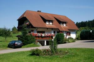 a house with flowers and a car on a road at Ferienwohnung in Seelbach