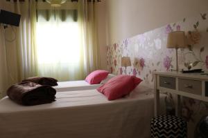 een slaapkamer met 2 bedden met roze kussens en een raam bij Quarto in Alvor