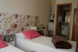 a bedroom with two beds with pink pillows at Quarto in Alvor