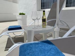 a white table with two glasses and a bottle of wine at Princesa Ico, cerca del mar in San Bartolomé