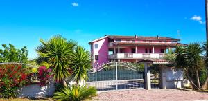 a pink house with palm trees and a fence at Villa Rita - Casa Vista Mare - Vasto Punta Penna in Vasto