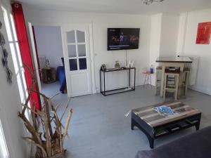 ein Wohnzimmer mit einem Sofa, einem Tisch und einem TV in der Unterkunft LE MARITIME in Le Havre