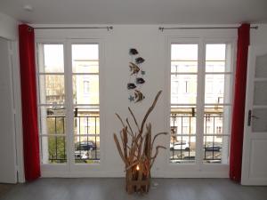 una habitación con 2 ventanas y un jarrón con una planta en LE MARITIME en Le Havre