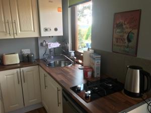 a kitchen with white cabinets and a sink and a counter top at Drumlin View Cabin 21c Deerpark Road in Ardkeen