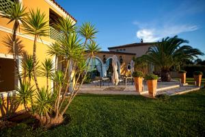 une maison jaune avec des palmiers et une cour dans l'établissement La Vigne de Ramatuelle, à Ramatuelle