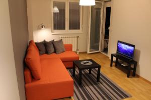 a living room with an orange couch and a tv at Skopje home 3 in Skopje