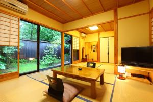 uma sala de estar com uma mesa e uma televisão em Yamashinobu em Minamioguni