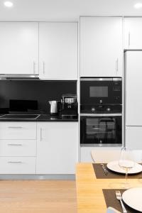 a kitchen with white cabinets and a table with wine glasses at East River - T4 junto ao Altice Forum - Braga in Braga
