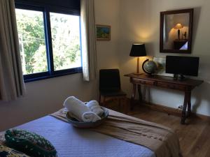 a bedroom with a bed with a desk and a window at Bela e Aconchegante Casa em Itaipava in Petrópolis +67 photos