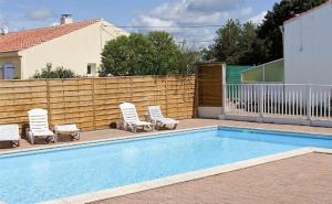 a swimming pool with lounge chairs and a fence at L'Océane ( Résidence La Joséphine ) in Les Sables-d'Olonne