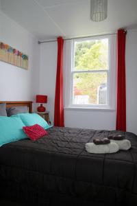 Schlafzimmer mit einem Bett mit roten Vorhängen und einem Fenster in der Unterkunft Whanga Bridge House in Whangamomona