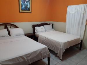 Hotel Rumbo al Sol في بلاياس: سريرين في غرفة بجدران برتقالية
