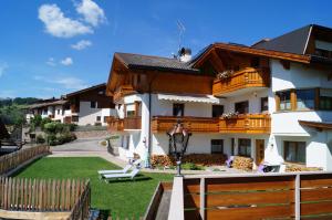 a house with a wooden fence and a yard at Apartments Salieta in Santa Cristina Gherdëina