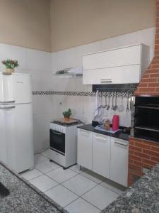 cocina con electrodomésticos blancos y pared de ladrillo en Recanto ferreira, en Olímpia