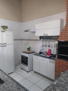 a kitchen with white appliances and a brick wall at Recanto ferreira in Olímpia