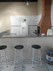 una cocina con tres taburetes frente a un mostrador en Recanto ferreira, en Olímpia