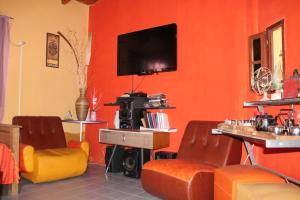 sala de estar con paredes de color naranja y TV de pantalla plana. en Hostel Rogupani en San Rafael
