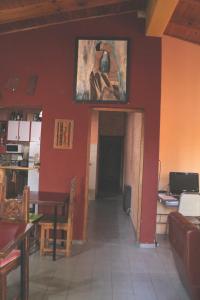 a dining room with a red wall with a painting on the wall at Hostel Rogupani in San Rafael