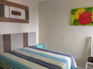 a bedroom with a bed with a striped blanket on it at Apto Verde Água in Mongaguá