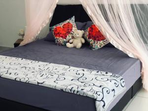 - un ours en peluche assis sur un lit avec des oreillers dans l'établissement Offer Spacious Studio KSL Residences Daya, à Johor Bahru