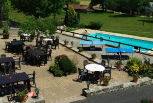 a group of tables and chairs next to a swimming pool at L'Auberge Fleurie in Le Nayrac