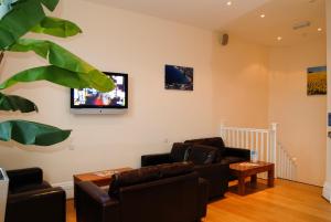 sala de estar con 2 sofás y TV en la pared en Berties Lodge, en Newquay