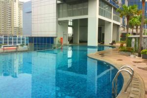a large blue swimming pool in front of a building at Spacious 2BR GP Plaza Apartment By Travelio in Jakarta