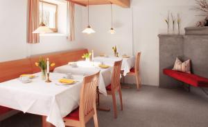 uma sala de jantar com mesas e cadeiras brancas em Haus Arnika em Mellau