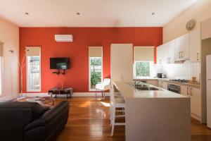 a kitchen with orange walls and a couch and a table at Healesville Cottage in Healesville
