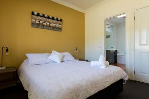 a bedroom with a large bed with white sheets at Healesville Cottage in Healesville