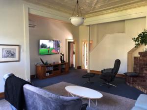 uma sala de estar com um sofá e cadeiras e uma televisão em 21morero em Taumarunui