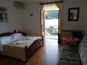 a bedroom with a bed and a couch and a window at Villa Kukuljica in Zaton