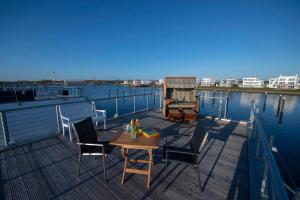 een houten terras met een tafel en stoelen op het water bij Schwimmendes Haus Jule in Olpenitz