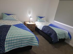 a bedroom with two beds and a table with a lamp at 123 Wilson - Arapiles in Horsham
