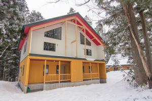 a yellow and white house in the snow at Alps Retreat Chalet by Morino in Hakuba