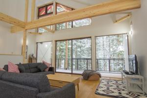 a living room with two couches and large windows at Alps Retreat Chalet by Morino in Hakuba