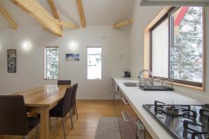 a kitchen with a wooden table and a dining room at Alps Retreat Chalet by Morino in Hakuba