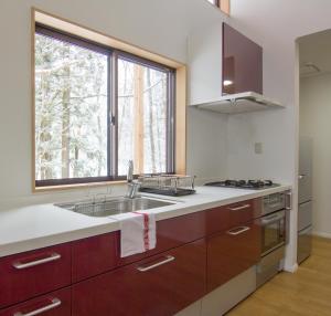 a kitchen with a sink and a large window at Alps Retreat Chalet by Morino in Hakuba +11 photos