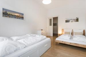 a white bedroom with two beds in it at Ruhiges Apartment am Rande des Szeneviertels in Dresden