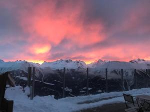 a sunset over a snowy mountain range with a red sky at Alpenlodge Kühboden in Fiesch