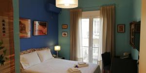 una camera da letto con un letto con pareti blu e una finestra di Filos Apt. under Acropolis ad Atene