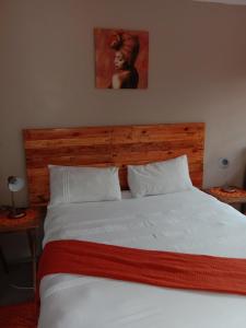 a bedroom with a white bed with a wooden headboard at Tap's Home Away from Home in Gaborone