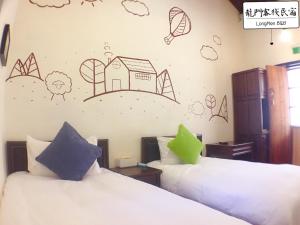 two beds in a room with drawings on the wall at Longmen Inn Bed and Breakfast in Jinning +5 photos